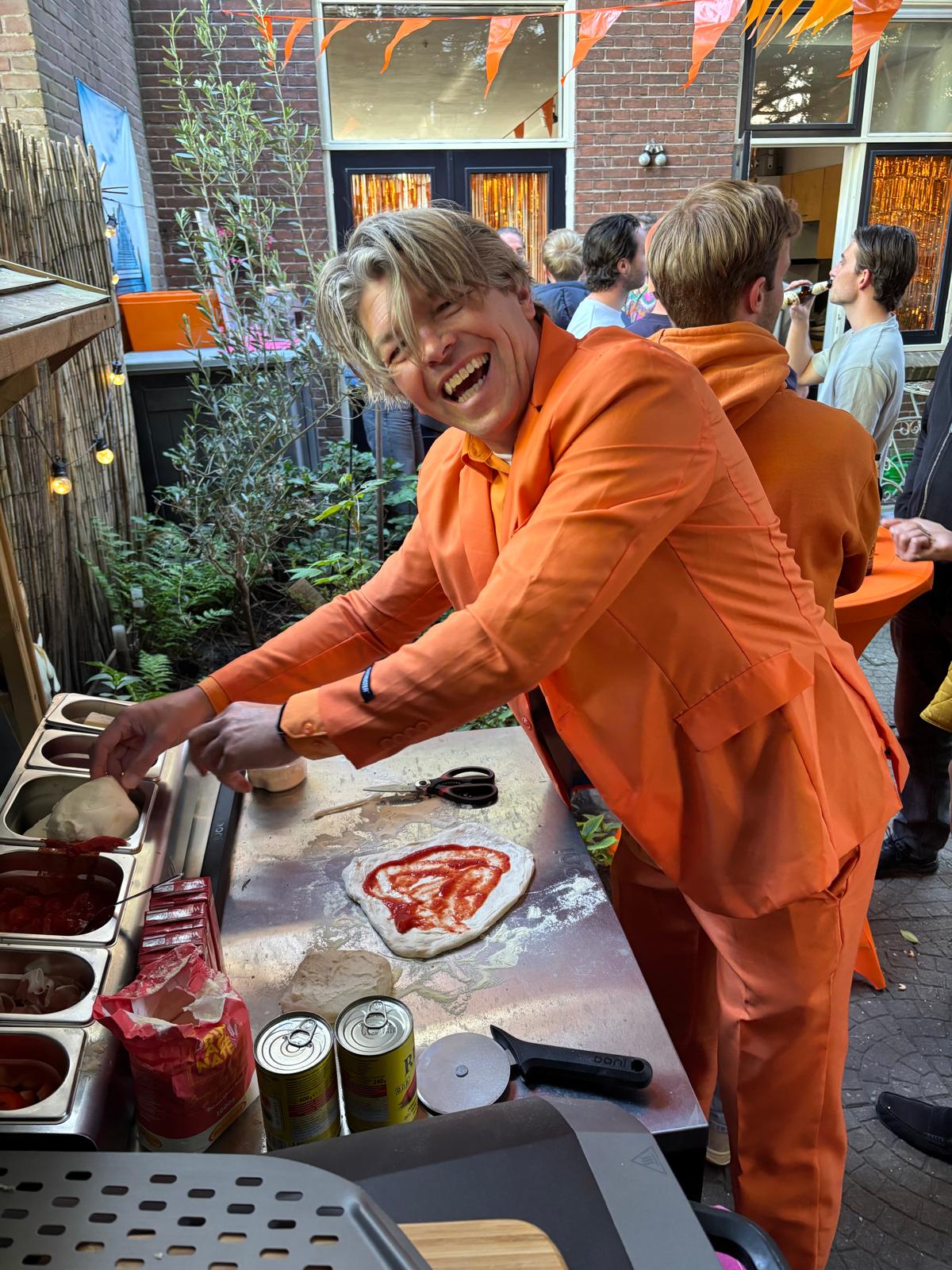 Onno in oranje pak bakt pizza's in de tuin tijdens het feest
